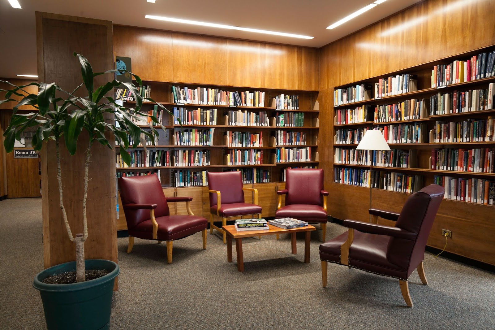 chairs surrounding a table with books in the background