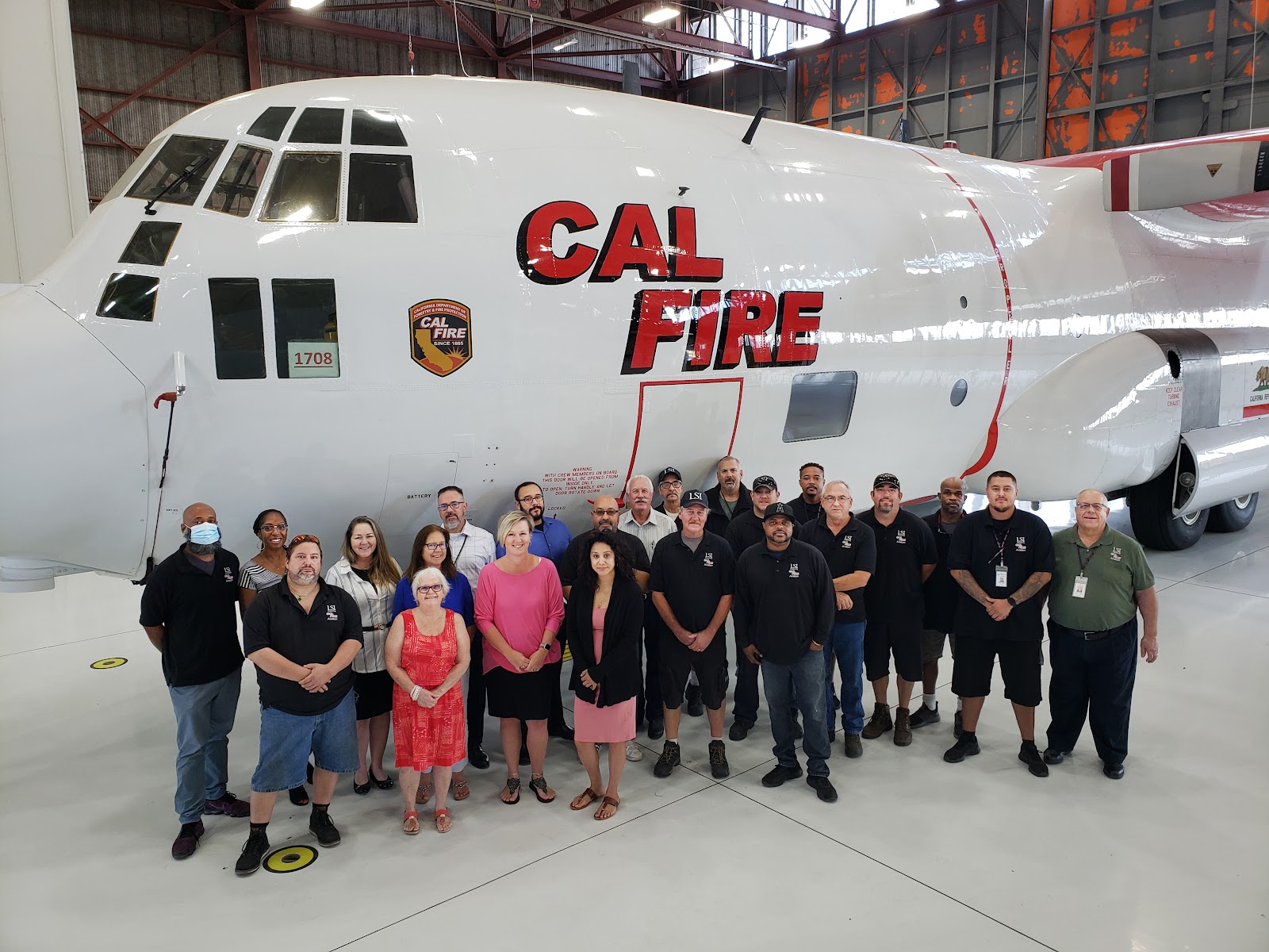 LSI employees assemble beside a former Coast Guard C-130aircraft. It is one of seven to be converted to an operational Airtanker capable of delivering up to 4,000 gallons of fire retardant.Row 1: Lance Larscheid, Warehouse;  Shirley Milke, Procurement;  Kathy Medina, Procurement; Desiree Smith, Procurement;  Mike Paulsen, Warehouse Lead;  Drew Owens, Helicopter Parts Room. Row 2: Adonis Williams, Helicopter Parts Room Lead;  Dawn Sealy, Aviation Logistician;  Lori Young, Aviation Logistician Lead;  Pat Hoffman, Procurement;  Rob O’Donnell, Procurement;  Stephen Horvath, Procurement Lead;  Tony Almora, Tool Room;  John Flovin, HazMat & Industrial Safety Coordinator;  George Hernandez, Warehouse;  Greg Smith, Senior Inventory Supervisor;  Robbie Turner, Warehouse;  Dameion Thomas, Fixed Wing Parts Room;  Mark Vossler, Senior Inventory Supervisor;  Dan Tollett, HazMat & Facility Maintenance;  Marc Stone, Tool Room;  Anthony Benavidez, Fixed Wing Parts Room;  John Firebaugh, Aviation Logistics Support Manager. Not in picture: Jason Farley, Fixed Wing Parts Room Lead;  Bill Busig, Fixed Wing Parts Room;  Tanner Slates, Fixed Wing Parts Room & Quantum Specialist (currently);  James Van Hook, Accounting