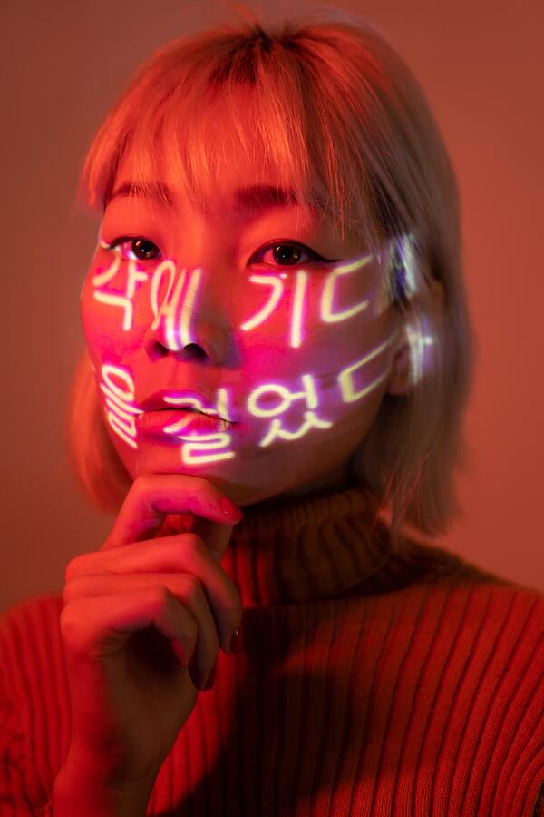 mulher asiática com escritas em neon sendo projetadas no rosto 