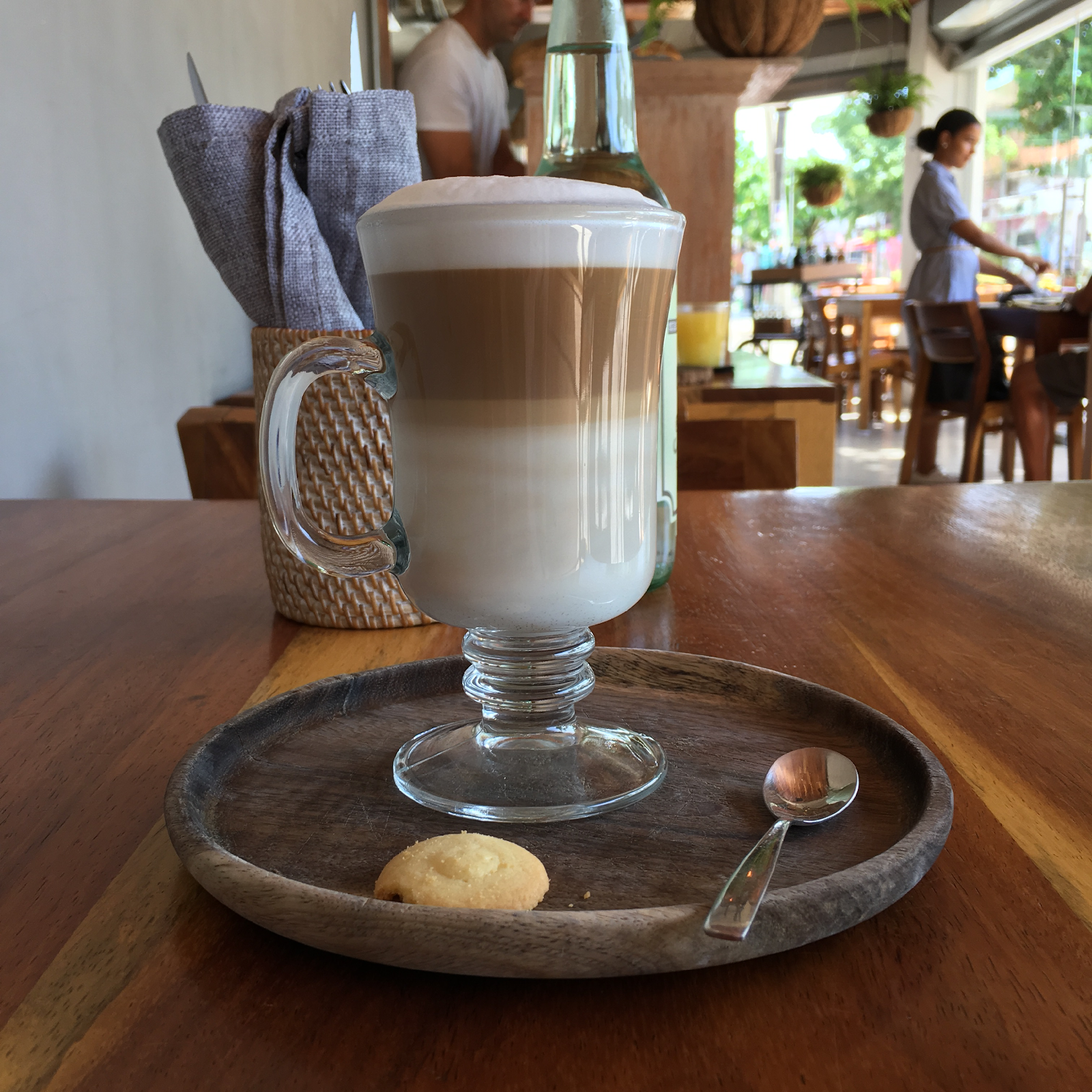 a glass of coffee on a wooden tray