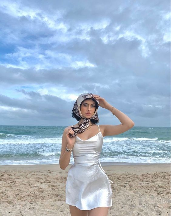 Woman wearing little white dress and colorful scarf on the beach