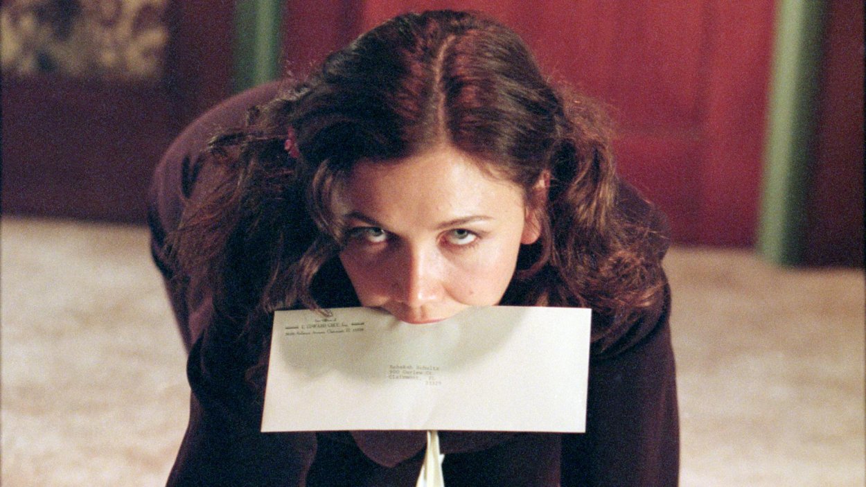 Lee Holloway on her hands and knees with an envelope in her mouth in Secretary