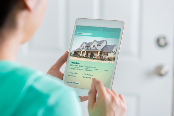 A woman browsing through house listings on her iPad