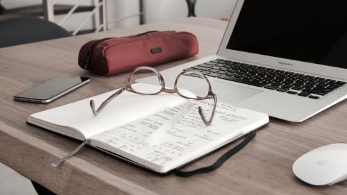 Desk with notebook and laptop from person making a written budget of t=how they plan to pay black their LendingClub personal loan. 