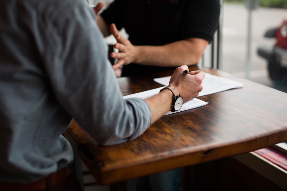 Two people discussing business over a table with documents