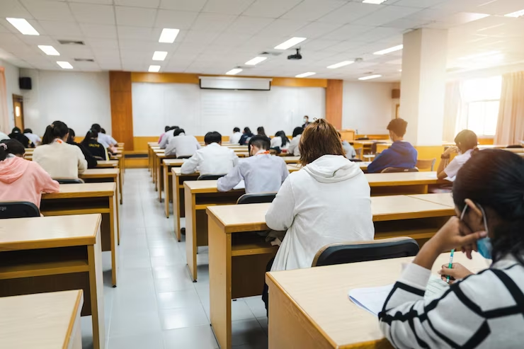 Students diligently writing their final examination papers in a classroom during the Cambridge University admission process.