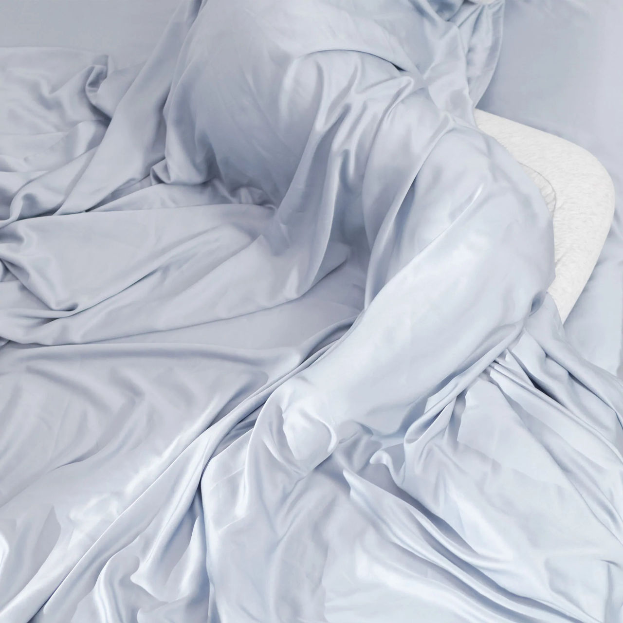 Hush Iced Sheets in light blue color draped over a sleeping person.