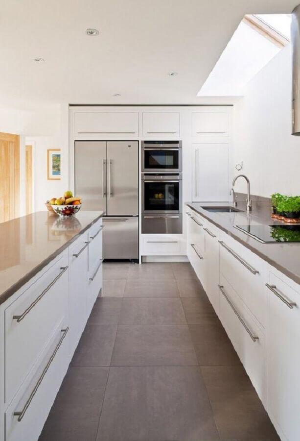 cozinha com estilo moderno com eletrodomésticos e puxadores cinza, bancada cinza e piso em tom neutro