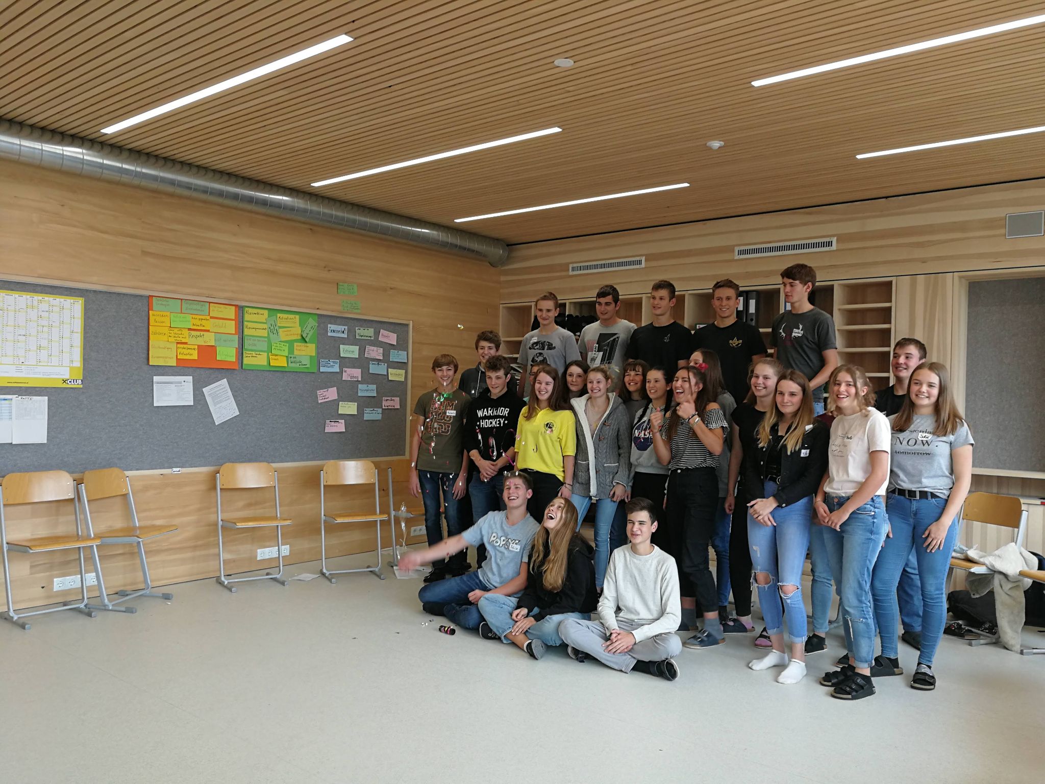 This image shows a group of several young adults in a classroom posing for a picture together.