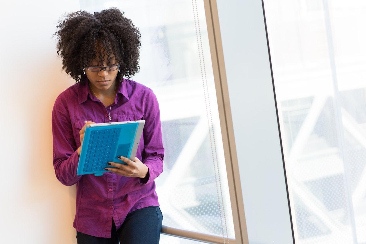 Image of woman leaning against wall writing notes. 