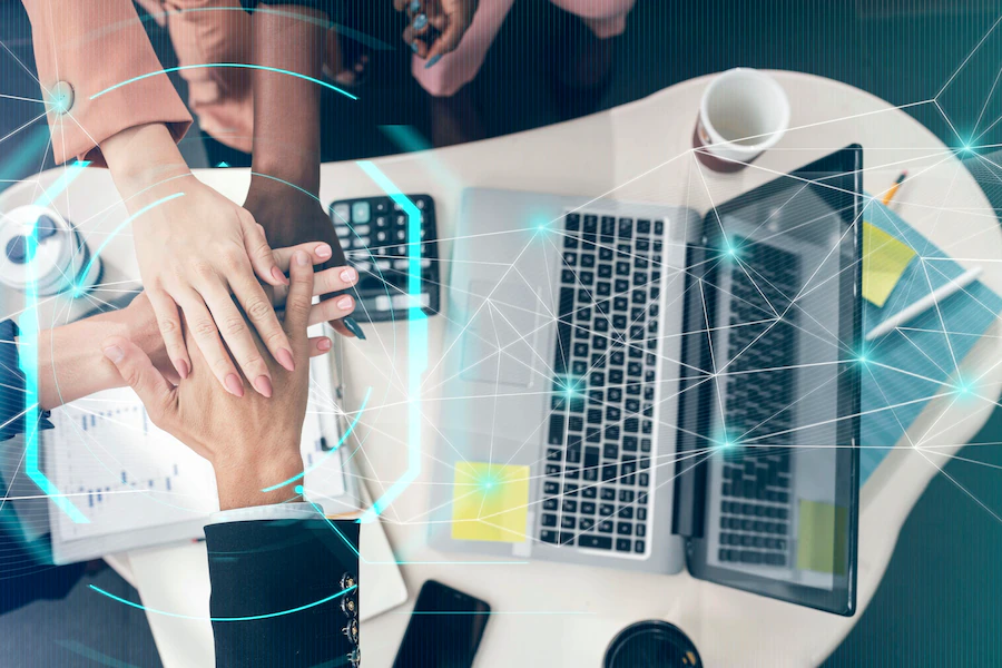 Inovação corporativa colaborativa: pessoas de negócio com as mãos colocadas por cima da outra, com símbolos tecnológicos ilustrados