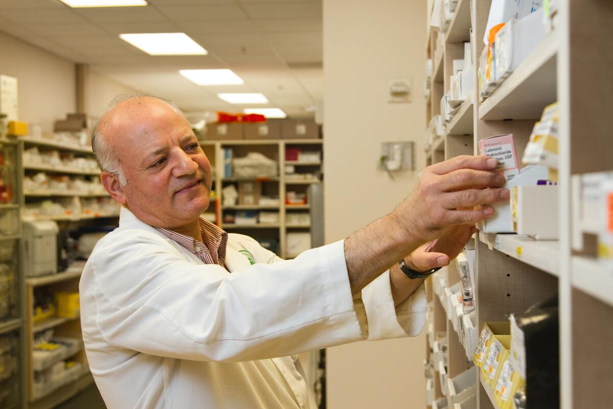 Foto di un farmacista che prende un farmaco da uno scaffale