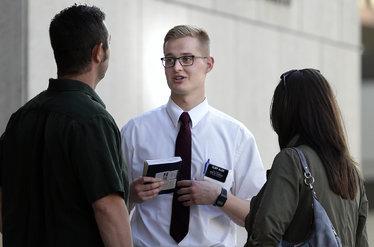  Forest Allen, a missionary with the Church of Jesus Christ of Latter-day Saints, offers a copy of the Book of Mormon to theater-goers outside the Marcus Center for the Performing Arts on Wednesday. A traveling version of the Broadway hit “The Book of Mormon” is playing at the Marcus. 