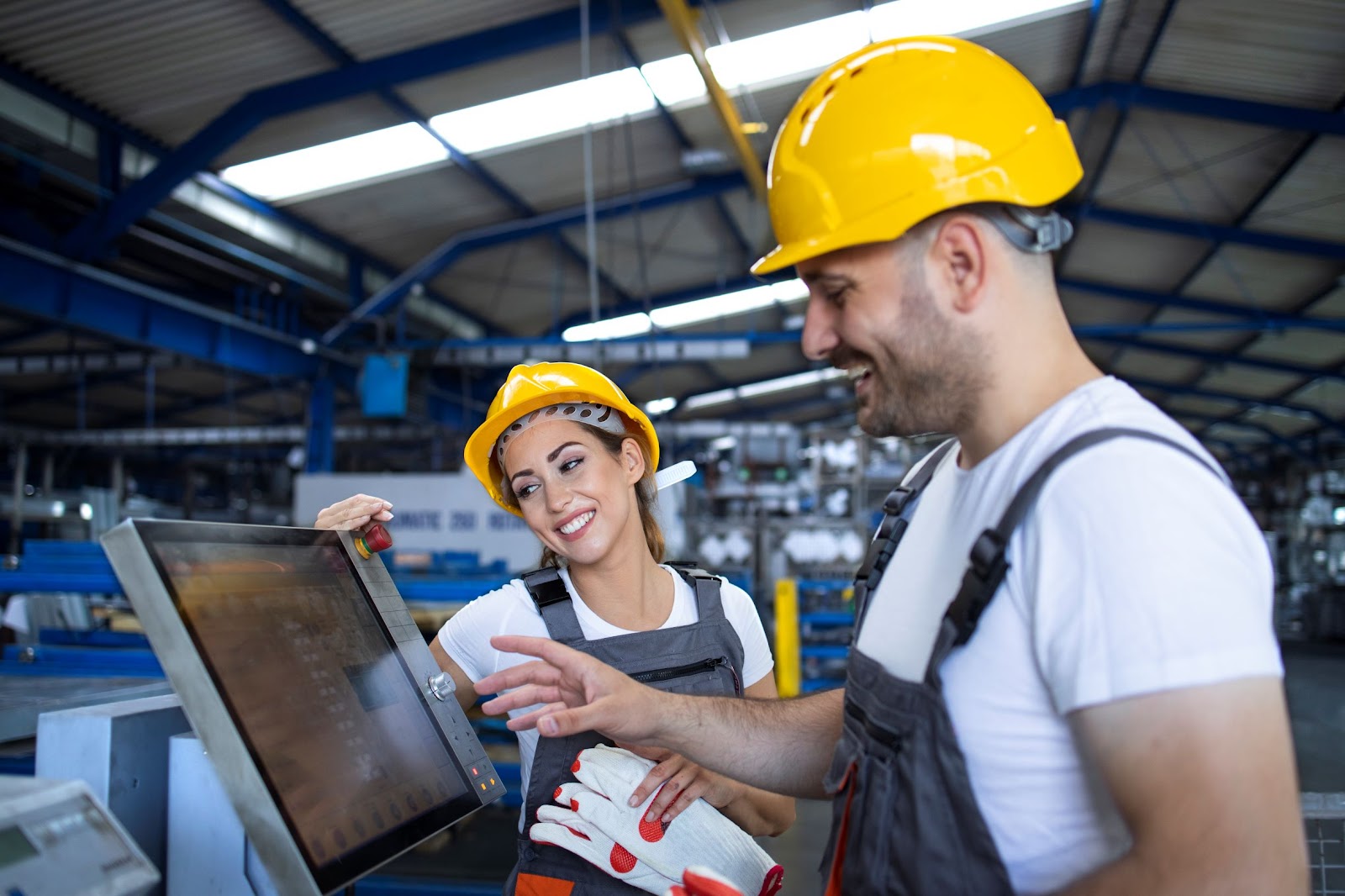 Imagem de um trabalhador, vestido com EPI, mexendo em uma tela touch de processos, mostrando a importância do uso de software de gestão em todos os setores!