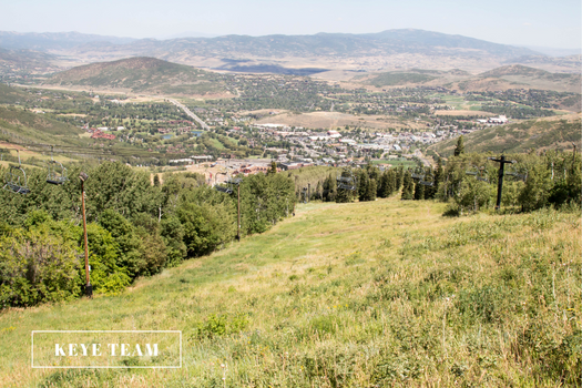 Image of ski hill in the summer filled with grass and the town below.