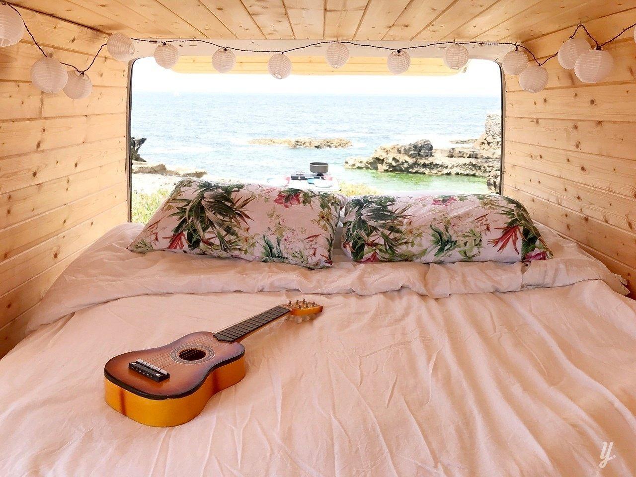 guitar on camper van with view of ocean