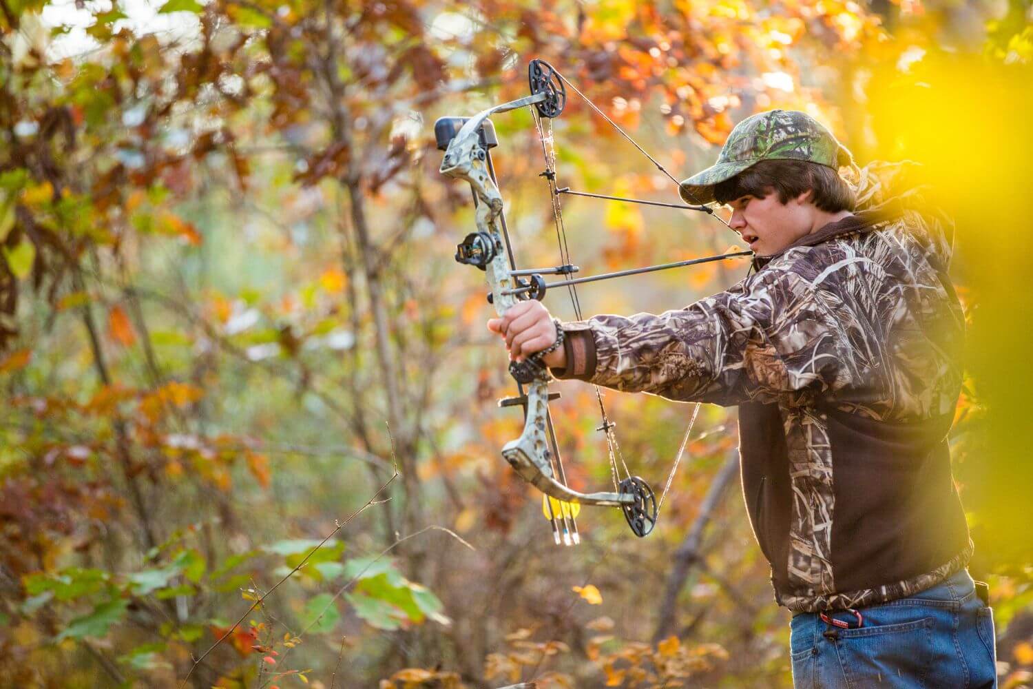 Man wearing camouflage while compound bow hunting