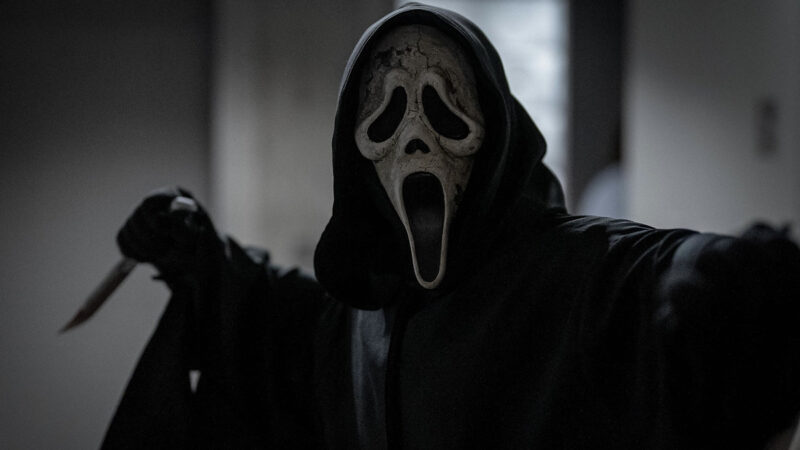 A killer wearing a Scream mask and a black cloak holds a knife