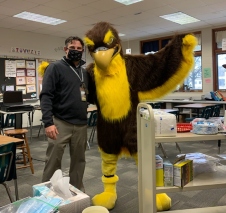Image of school mascot in costume and assistant principal delivering coffee