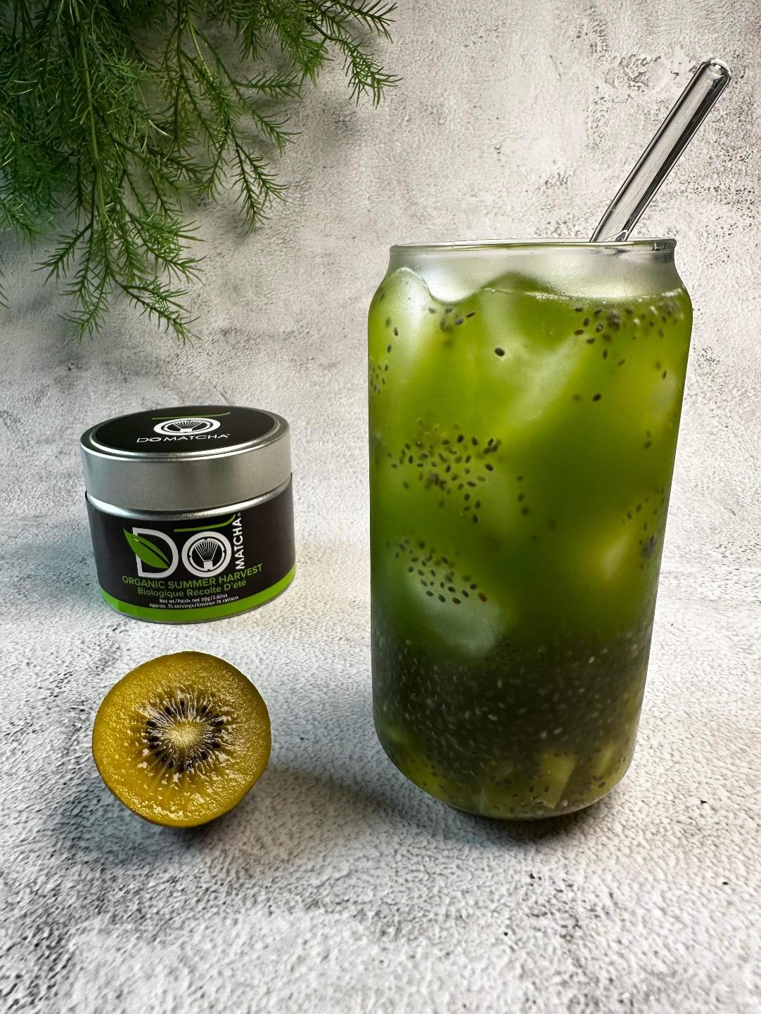A green drink in a glass jar next to a half of a kiwi

