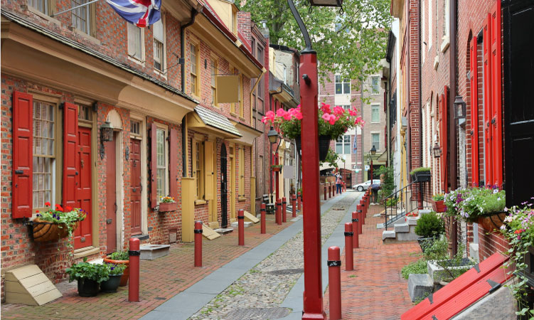 Brick townhomes with red wooden shutters line historic Elfreth’s Alley in Old City, Philadelphia.