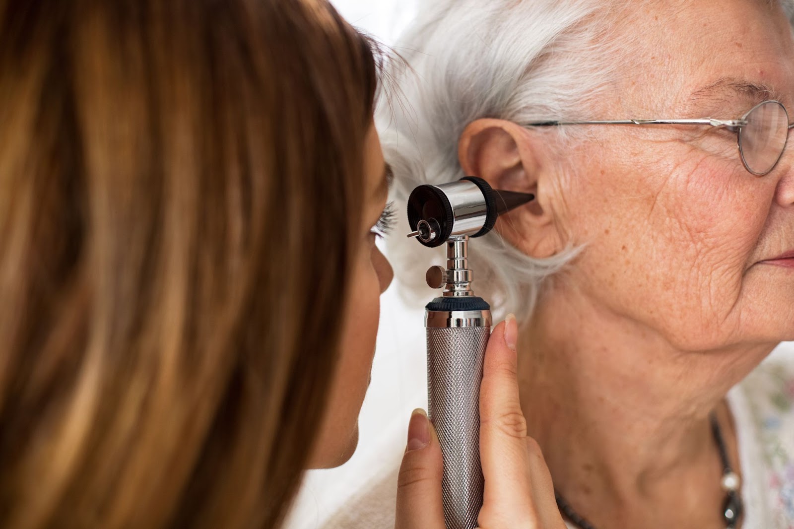 female audiologist looking into an elderly woman's ear