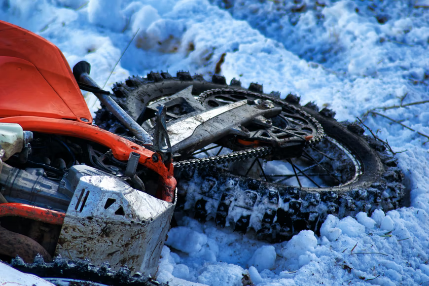 A red motorcycle lying on snow. If your reflexes are slow because of old age, it can be dangerous to ride your motorbike.