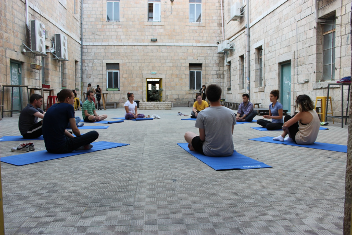 A group of people sitting on the ground in a courtyardDescription automatically generated with low confidence