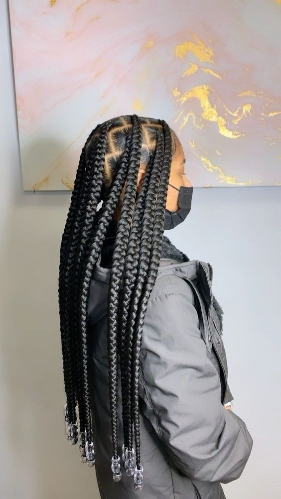Side view of a lady with her jumbo sized braids and transclulent beads