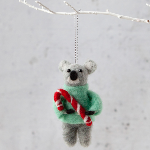 a christmas ornament with a teddy bear holding a candy cane