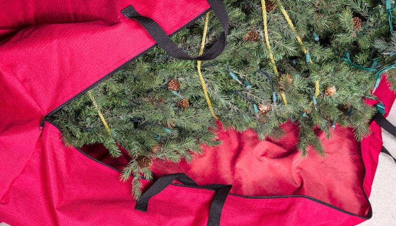 An artificial Christmas tree in a red Christmas tree storage bag