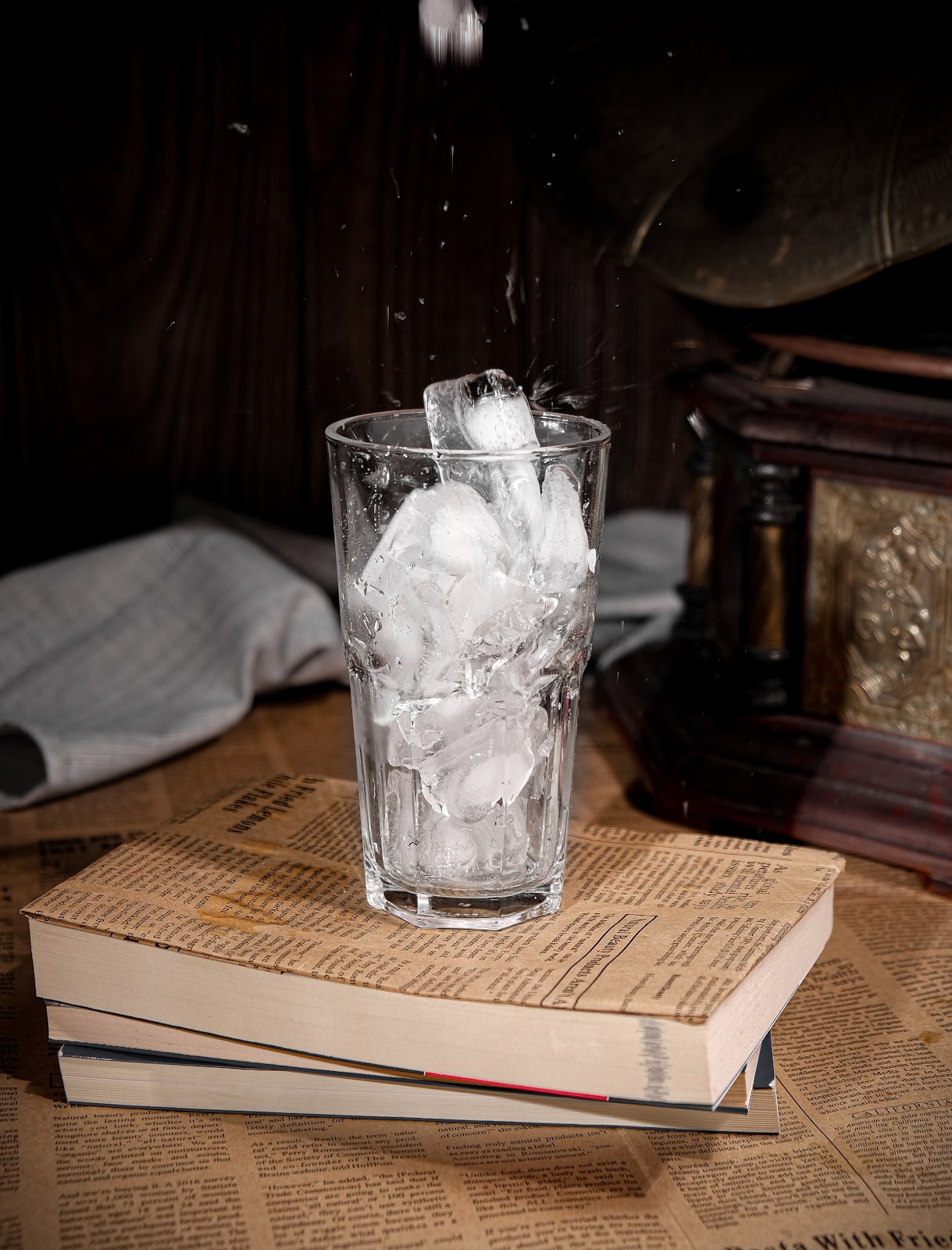 A glass of melting ice rests upon a stack of books.