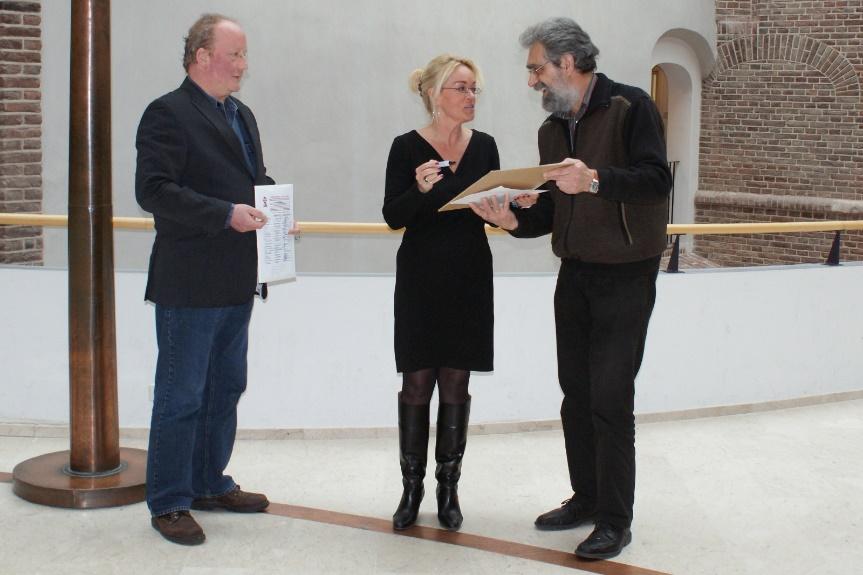 SP'ers Wim Musch (links) en Johan Oonk (rechts) bieden wethouder Schriks (midden) een petitie aan voor het behoud van betaalbaar openbaar vervoer in Zutphen