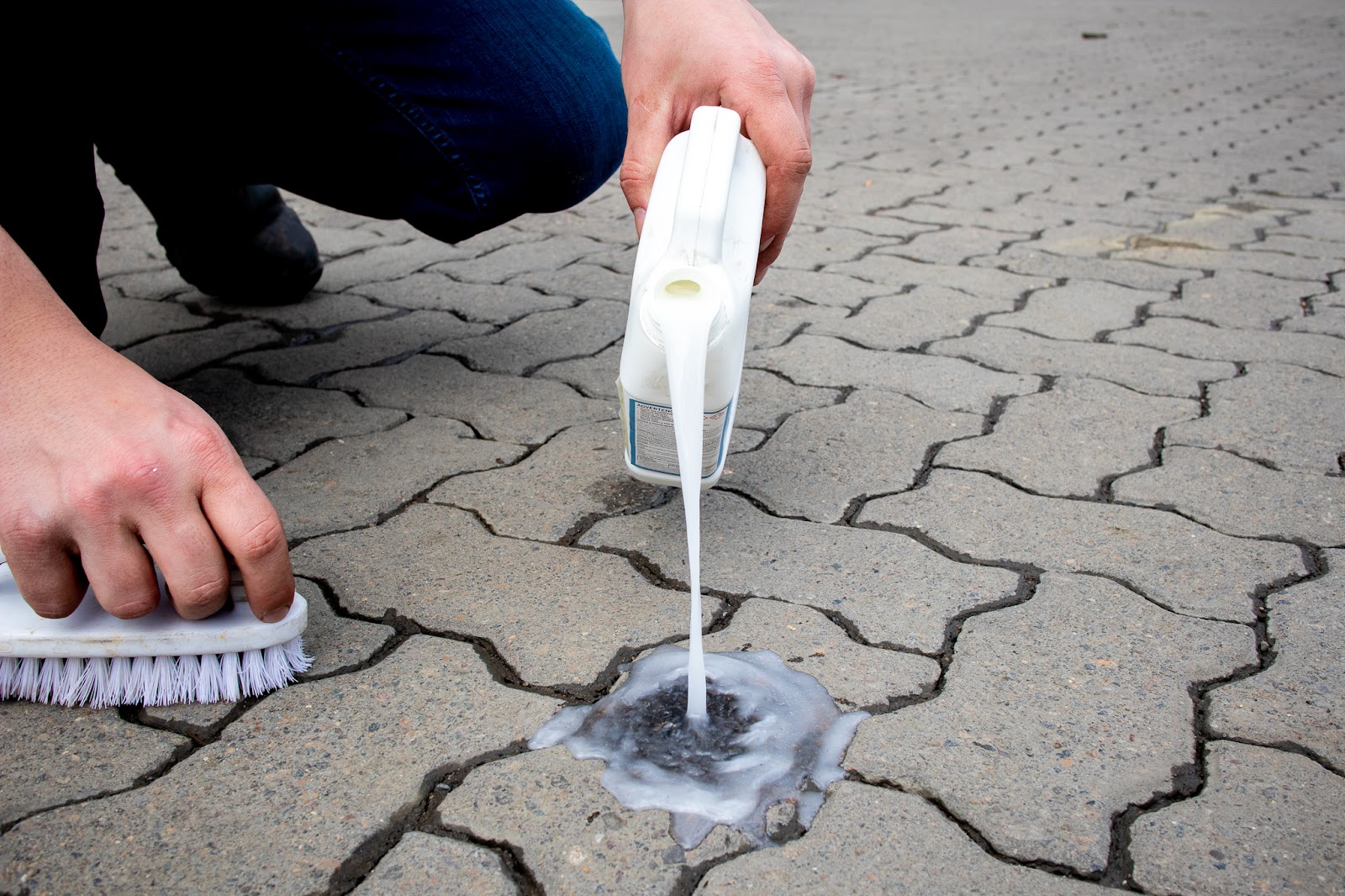 Pouring Surebond Oil Extractor onto paving stones.