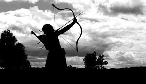 The silhouette of a girl shooting an arrow into a cloudy sky.
