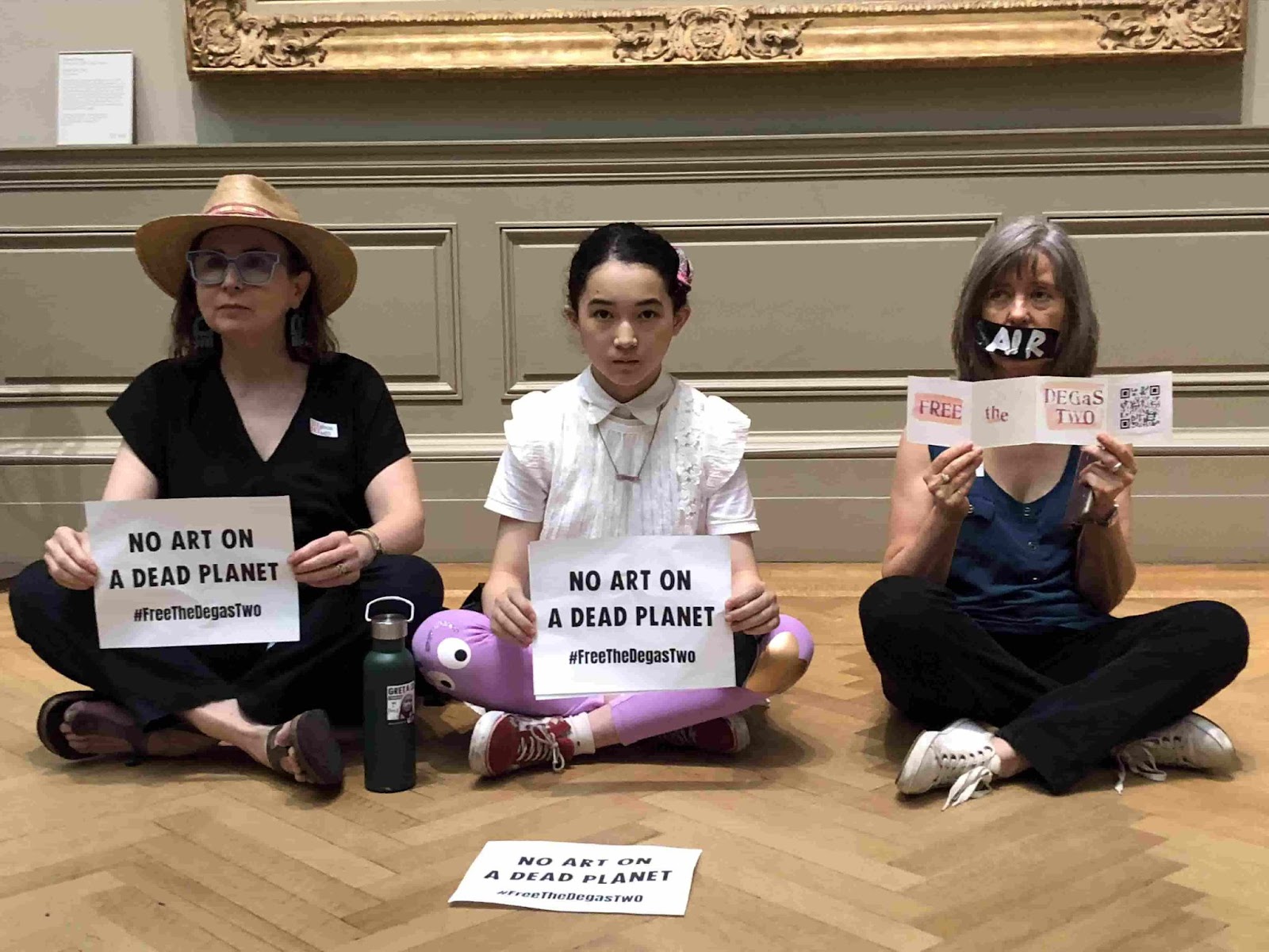 Rebels sit silently with signs that say 'no art on a dead planet'.