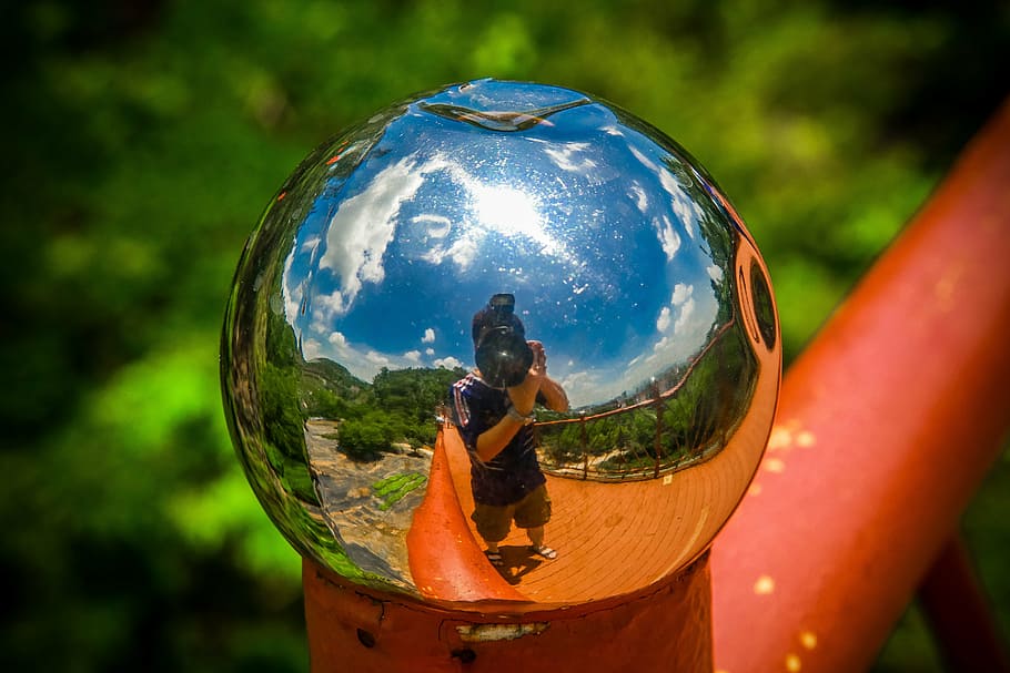 A reflective globe staircase knob showing the photographer's image capturing the photo. 