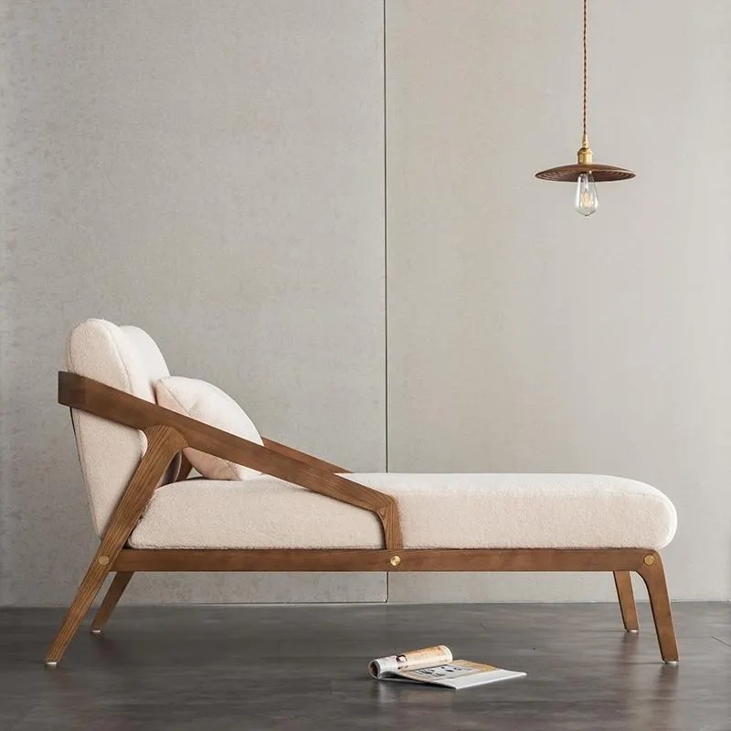 White chaise lounge upholstered in fabric with wooden frame. 
