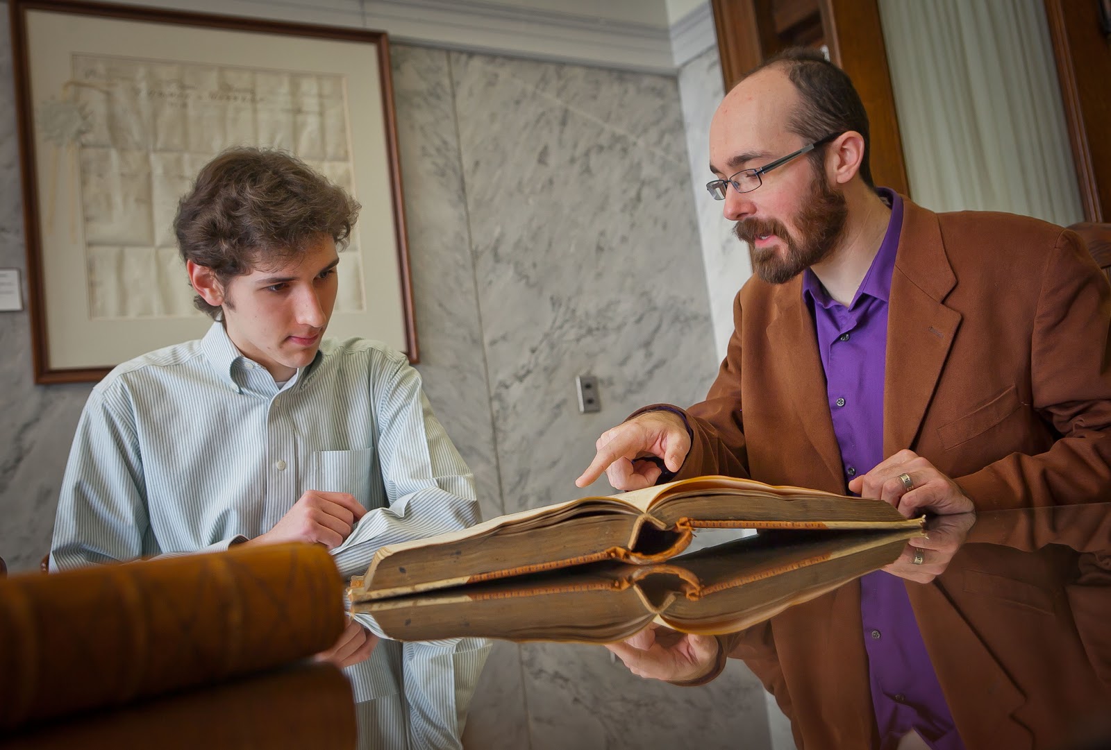 professor and student looking at an old book together