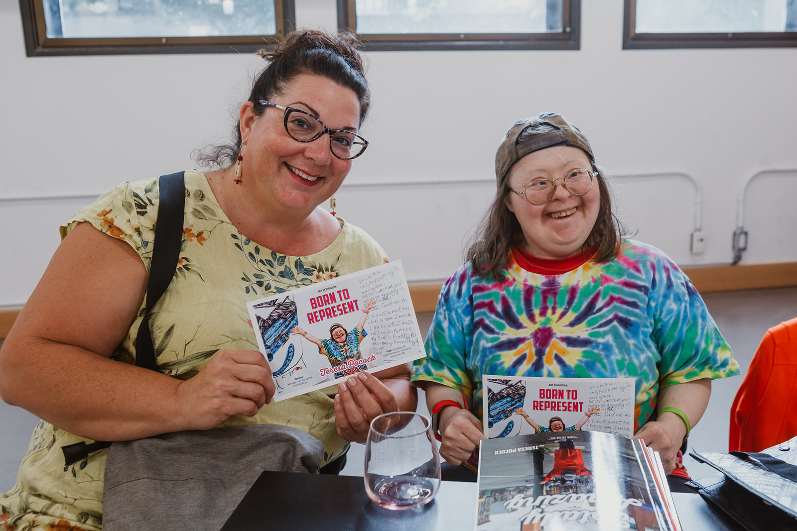 Friends Liz and Teresa pose for a photo while holding up Teresa's Born To Represent cards. Photo: This Is It Studios.