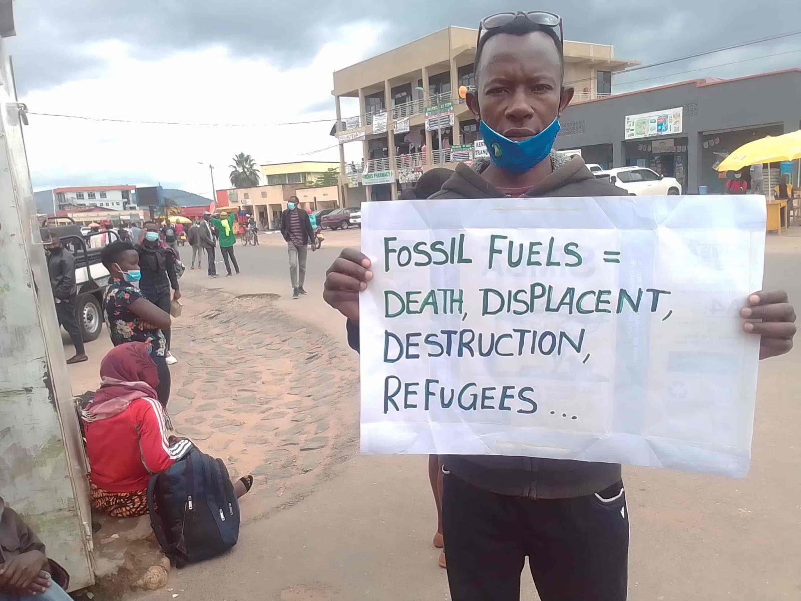 A rebel in a Rwandan city street holds a sign against fossil fuels.
