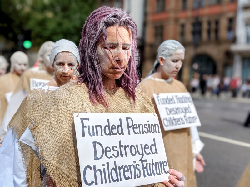 A penitent rebel with a sign "funded pension destroyed children's future"