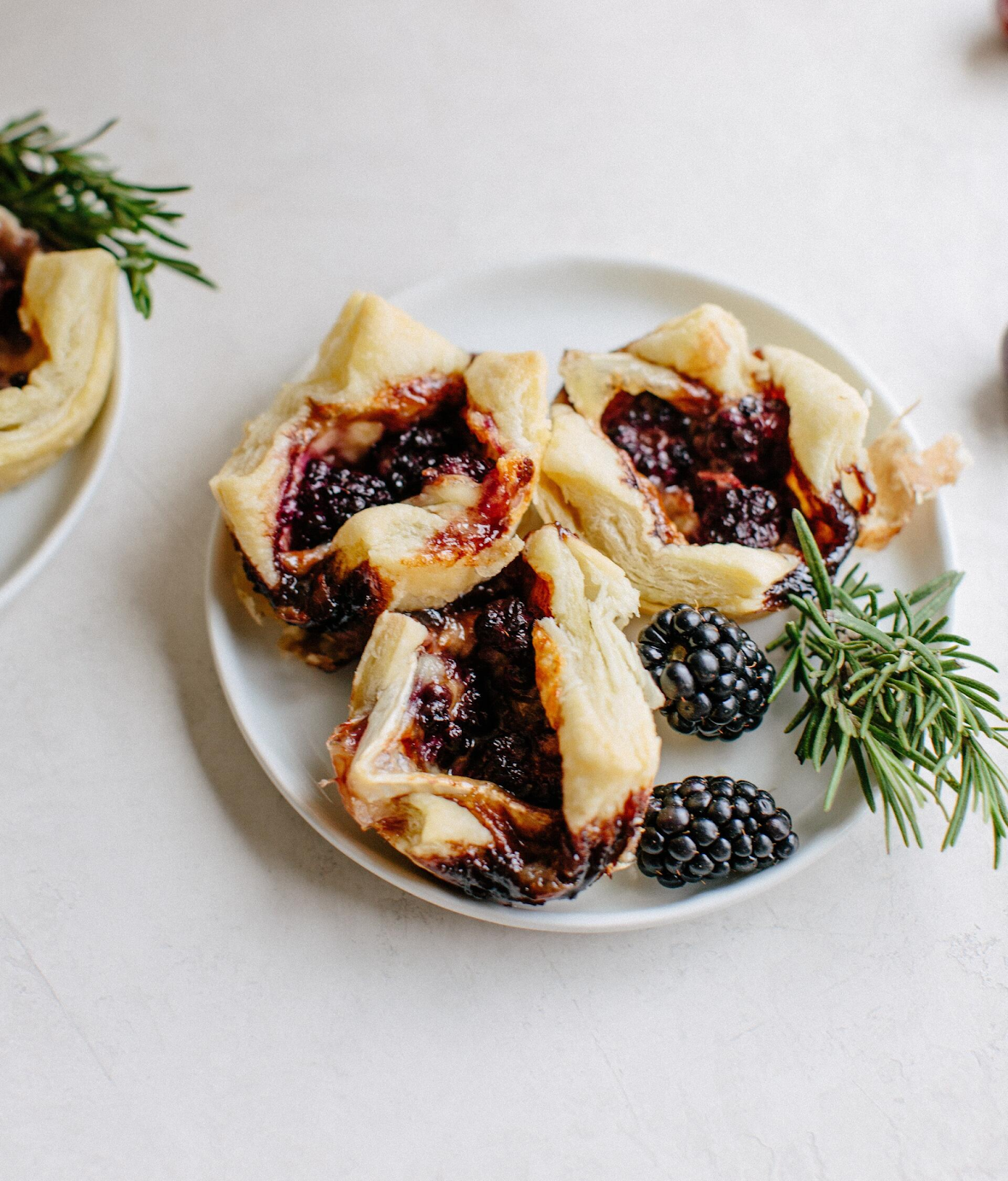 3 balsamic blackberry and brie puff pastry bites on a plate