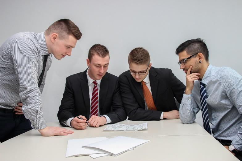 A group of men looking at a paper

Description automatically generated with medium confidence