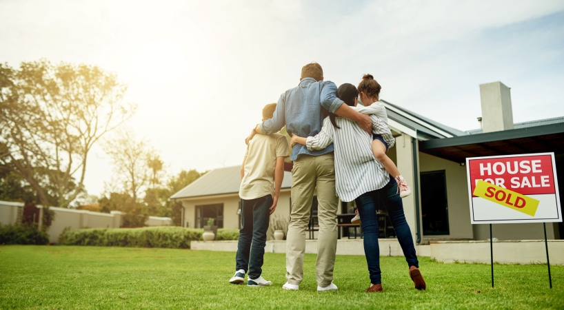 Young family in front of newly purchased home.