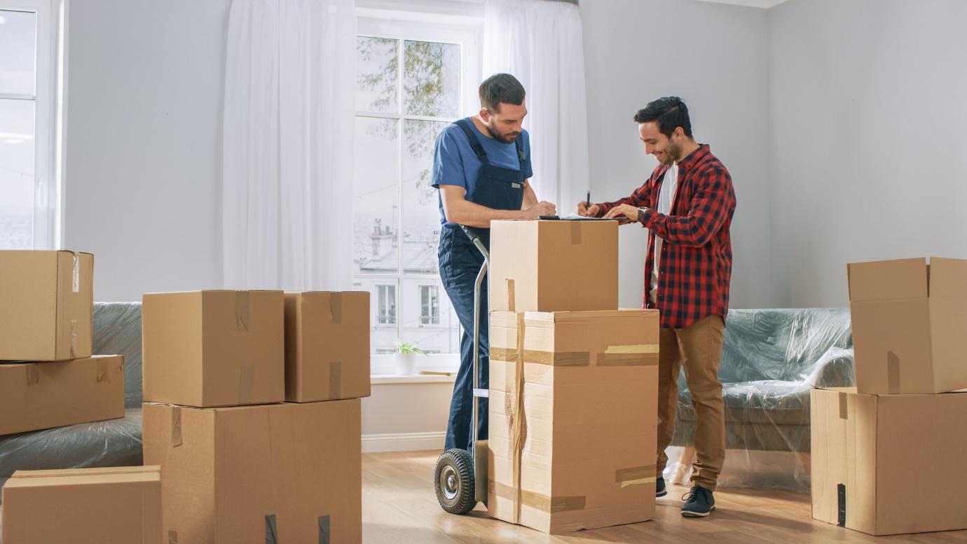 professional moving company unloading boxes in new home and getting signatures from homeowner