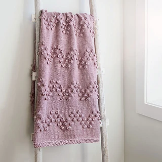 pink knitted blanket with chevrons made from bobble stitches on blanket ladder