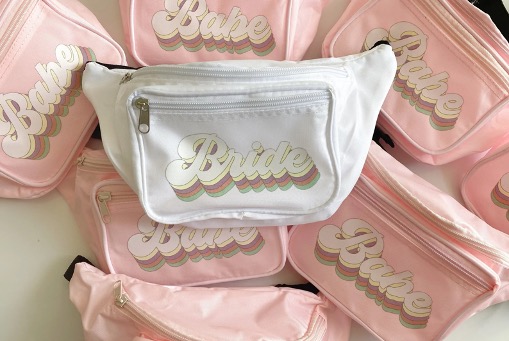 photo of white "bride" fanny pack with pink "babe" fanny packs