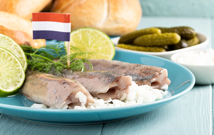 Khám phá tour du lịch Hà Lan - Món cá trích sống ăn kèm với bánh mì, dưa muối, chanh và hành tây