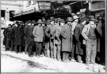 Men in overcoats and bowler hats, in what appears to be a depression-era photo, standing in line, presumably for lunch or jobseeking.